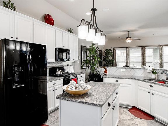 Kitchen with granite counters and black appliances. Upgraded lighting over the island.