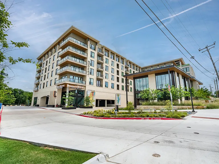 Street-facing Dallas community with ground-level cafe access, landscaped walkways, and contemporary architecture anchoring a connected neighborhood setting.