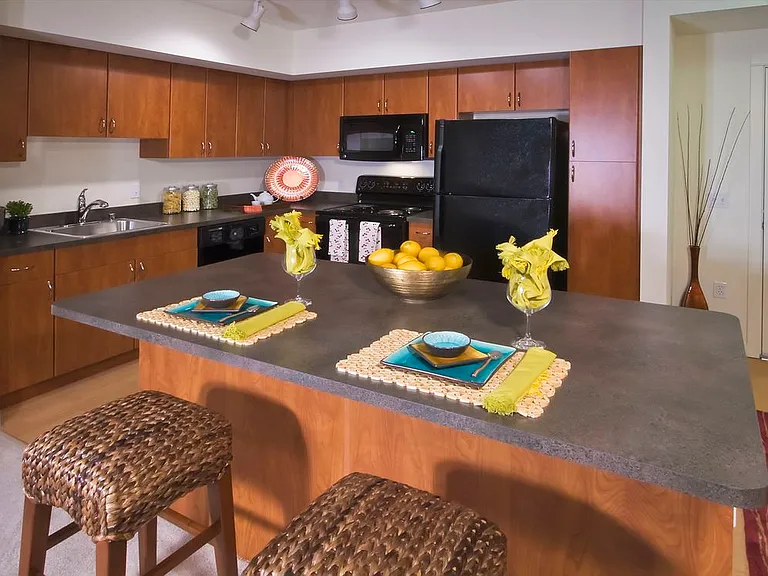 Classic Package I kitchen with cherry cabinetry, grey laminate countertops, black appliances, and hard surface flooring