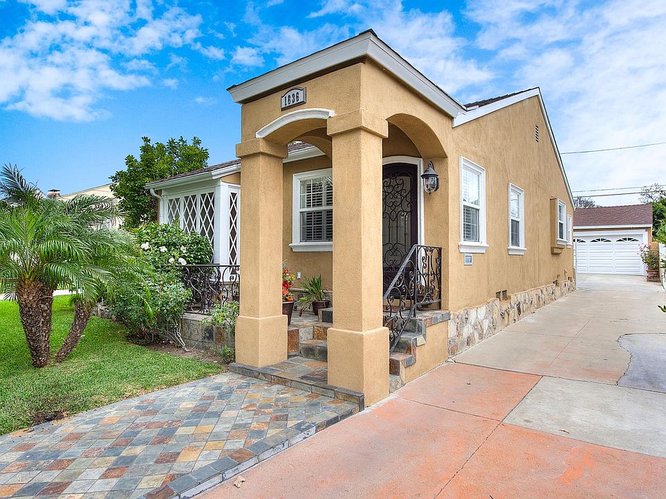 Fully landscaped front yard with long, elongated driveway to a gated backyard which houses 2 car garage.