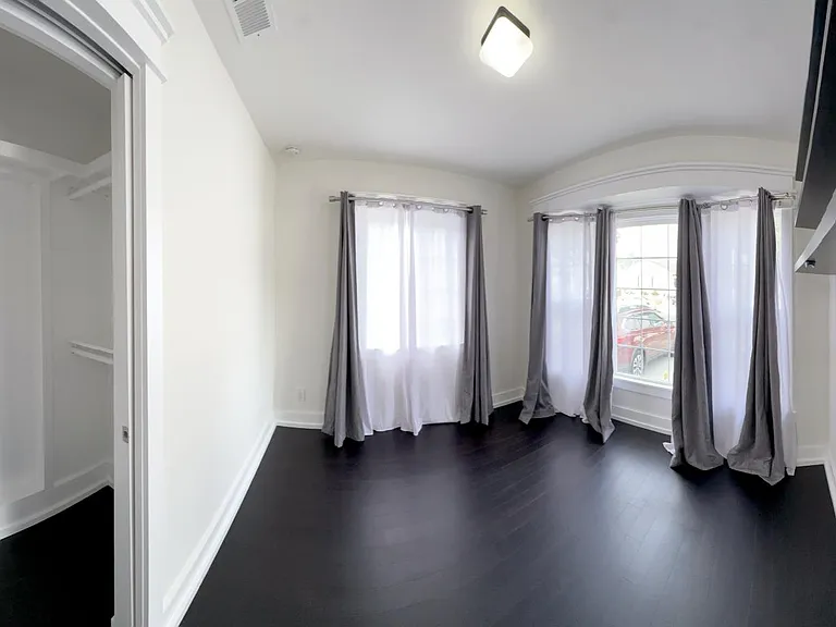 Panorama view of first bedroom with large bay window and step-in closet