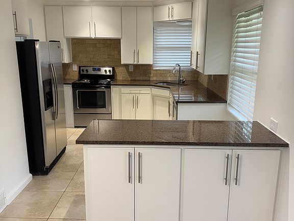 The kitchen features a double-door refrigerator/freezer, an electric stove/oven and a dishwasher.