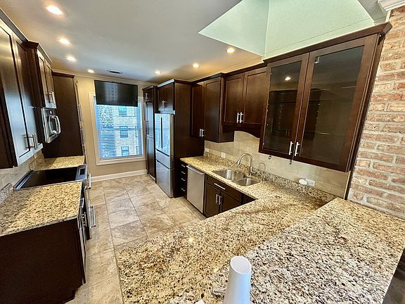 Recessed lighting, skylight, granite countertops, terrazzo tile floors and exposed brick wall