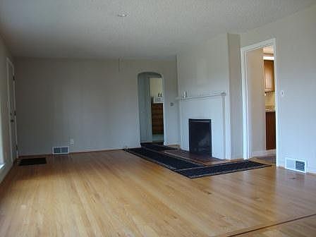Large living room showing fireplace and gleaming refinished hardwood floors.