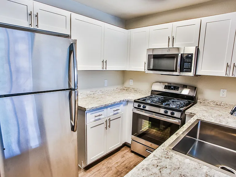 Fully equipped kitchen with stainless steel appliances, white shaker cabinets, and granite counters.