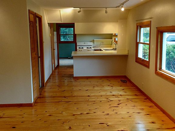 View from the living room to the dining area, kitchen beyond, and bedroom beyond