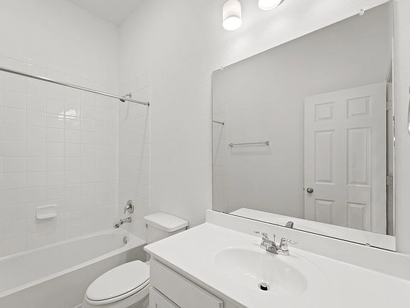 The second bath features tile flooring, white cabinetry and light countertops and a shower tub combo
