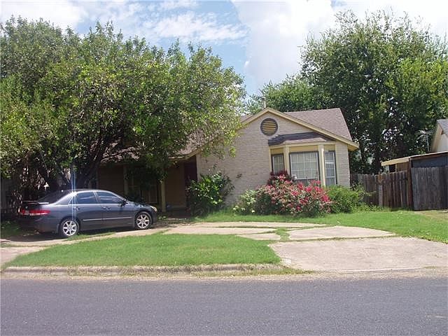 Cute home with a circular driveway, large tree, bay window, and front porch.