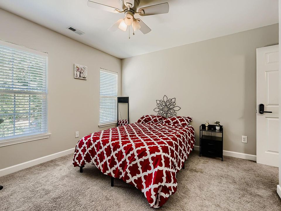 Comfortable bedroom with carpeted floors, ceiling fan, and two windows with blinds for adjustable natural light.