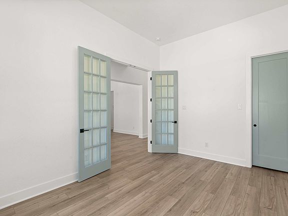 An additional view of the study featuring French doors, beautiful floors, custom painted doors and a
