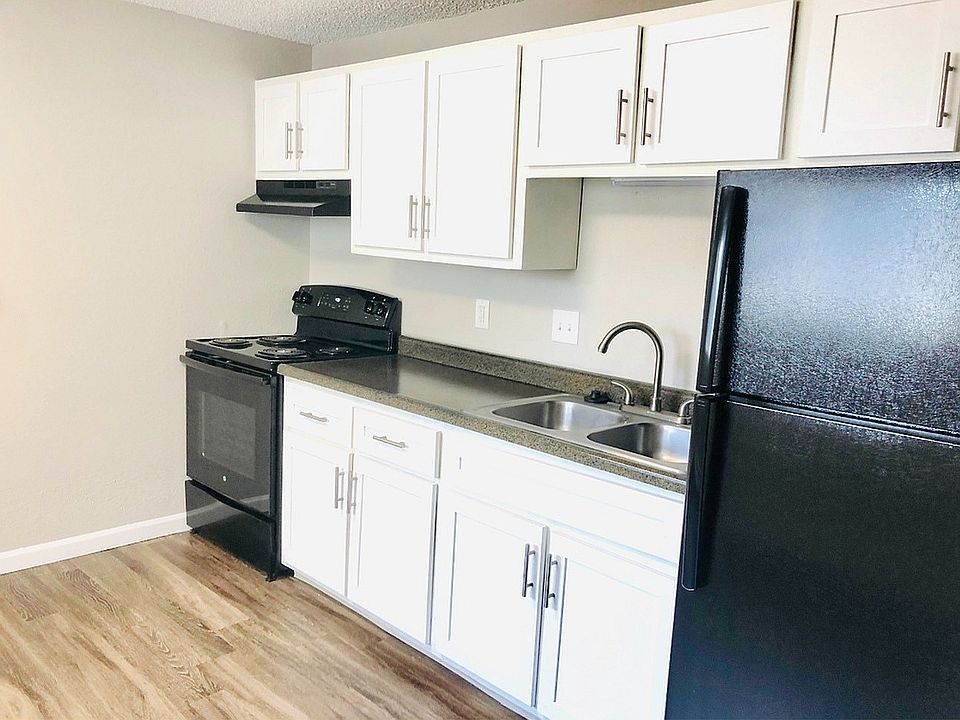 Modern kitchen with sleek black appliances, stylish white cabinetry, and elegant wood flooring.