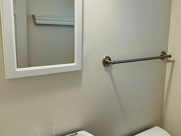 Bright and clean half-bathroom featuring a classic pedestal sink, a mounted mirror, and modern chrome fixtures.