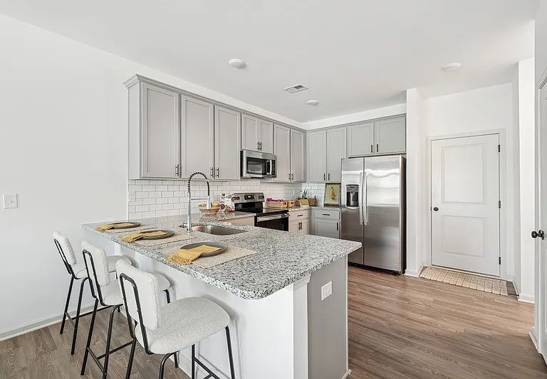 View of the kitchen and entry hallway. Offering bar seating, plenty of cabinet space and granite countertops.