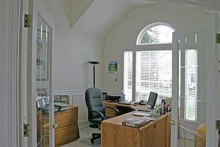 French doors lead to office with cathedral ceilings, wainscoting and closet