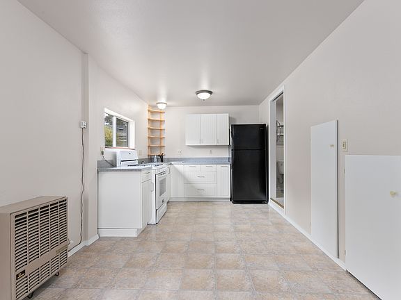 Corner sink, full sized refrigerator and gas stove with new flooring and freshly painted walls.