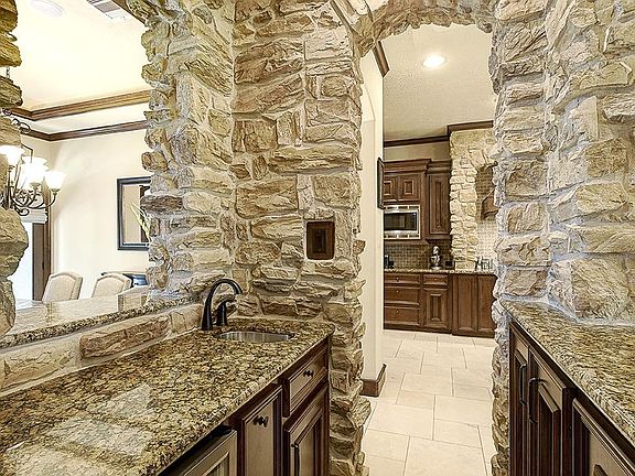 Wet bar with wine refrigerator, stainless steel sink and granite countertops.