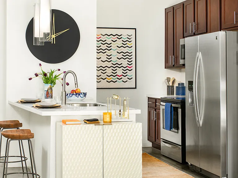 Apartment kitchen with stainless steel appliances, quartz countertops and polished concrete flooring.