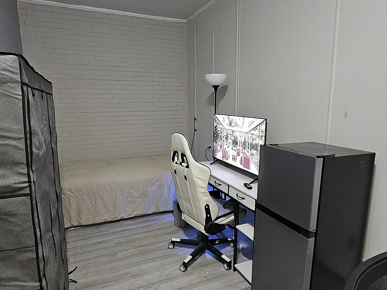 Private bedroom with a full bed, work desk setup, and in-room mini fridge for added convenience.