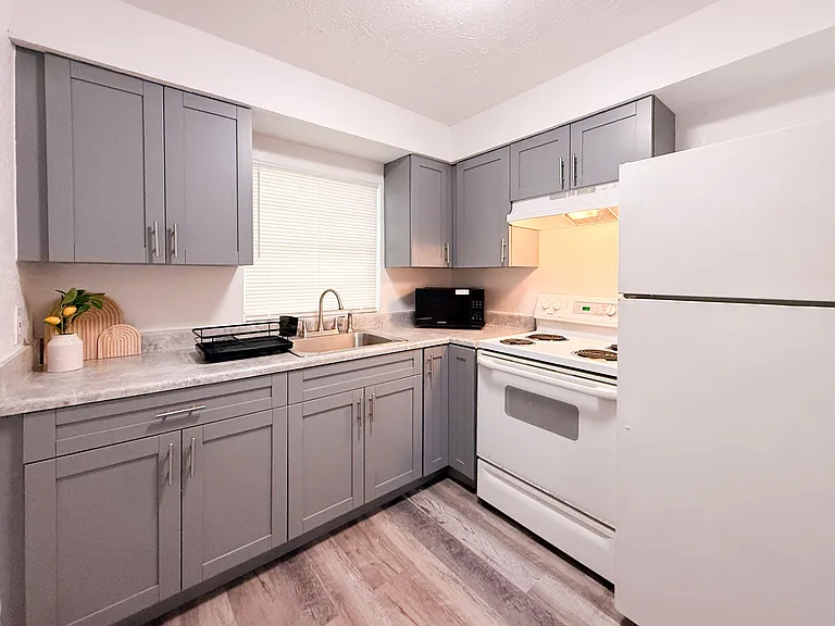 Updated U-shaped kitchen with ample cabinet storage, laminate counters, and a full appliance set including range and fridge.