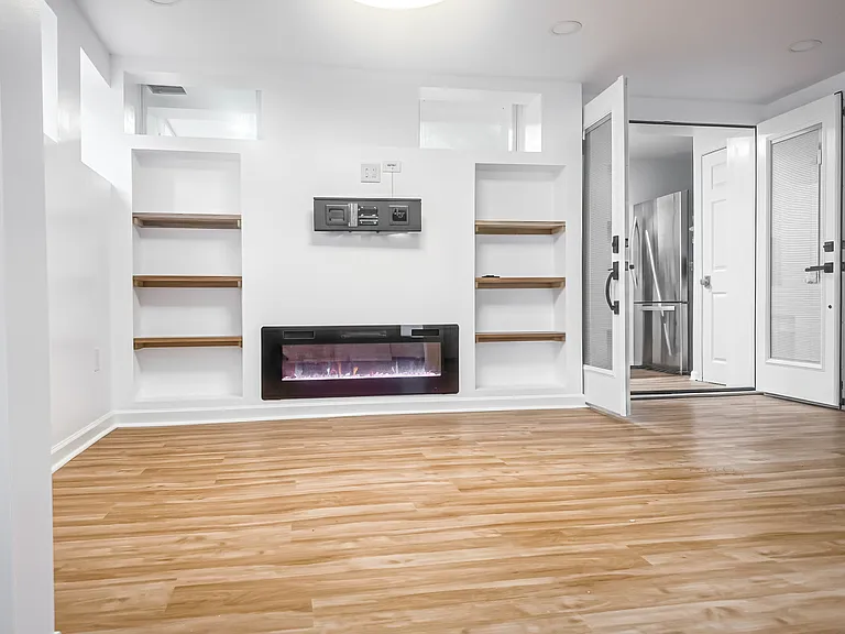 Private enclosed three-season room with French doors, multiple windows, updated flooring, and bright natural light.