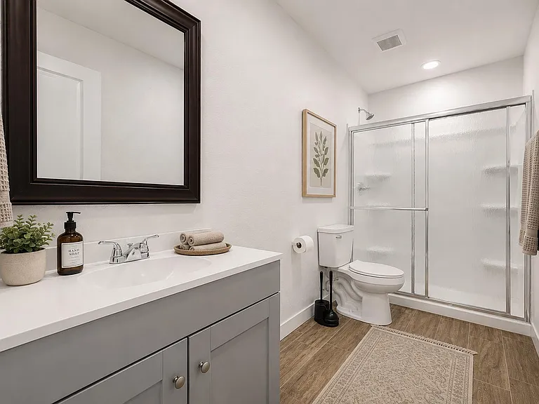 Updated full bath with wide vanity and large mirror, plus a tub/shower combo with sliding glass doors for easy upkeep.