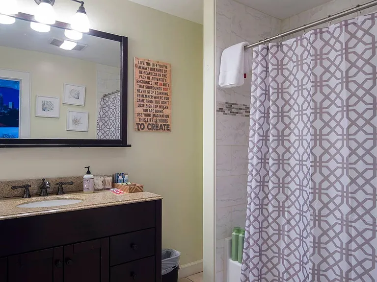 Full master bathroom with tub/shower, vanity with storage, and storage area beyond shower.