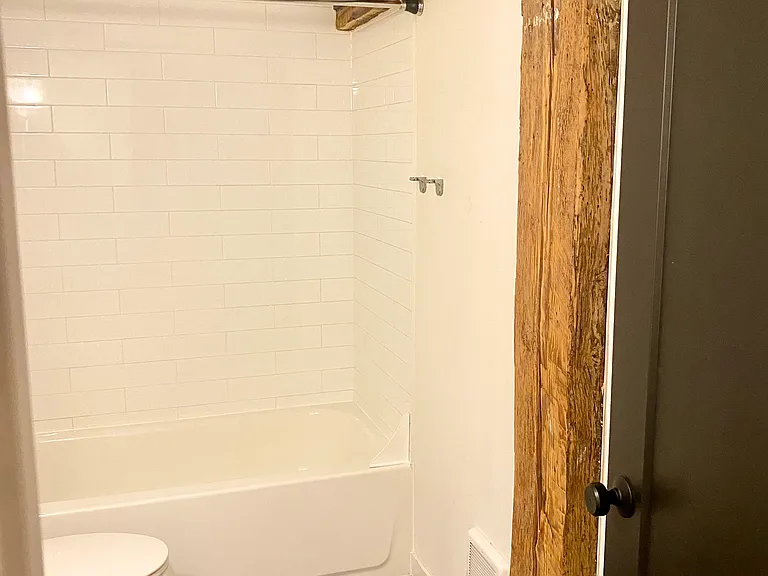 Bathroom with designer tile and one hundred year old wooden post, original to the structure