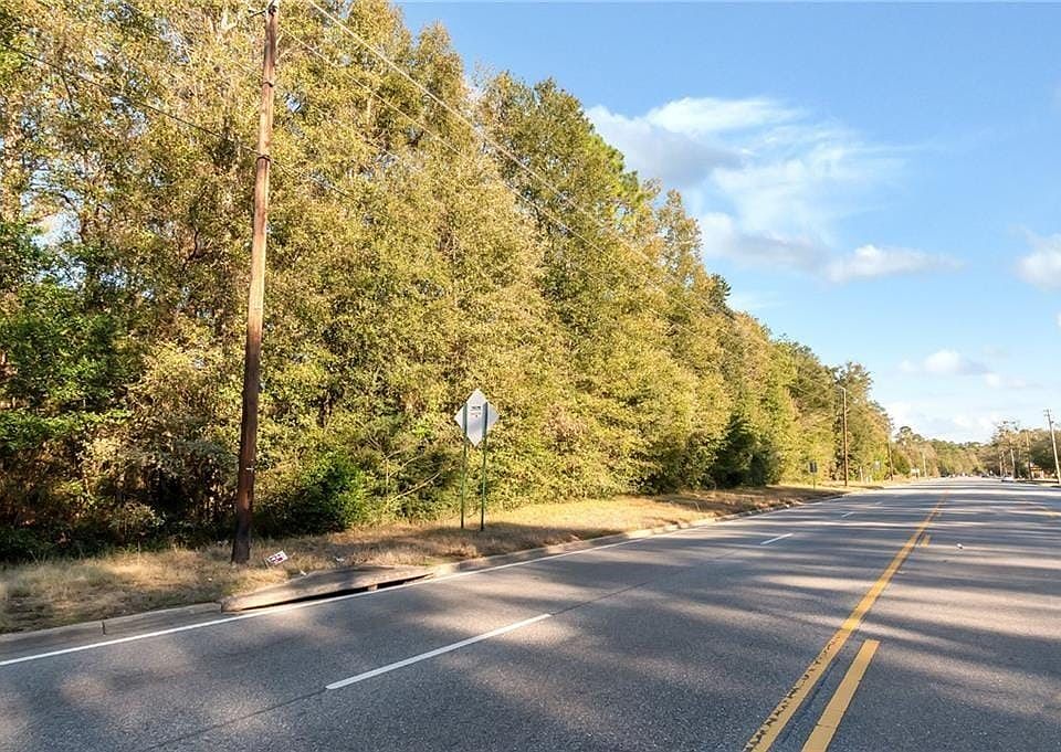 View of asphalt road featuring a forest view and curbs