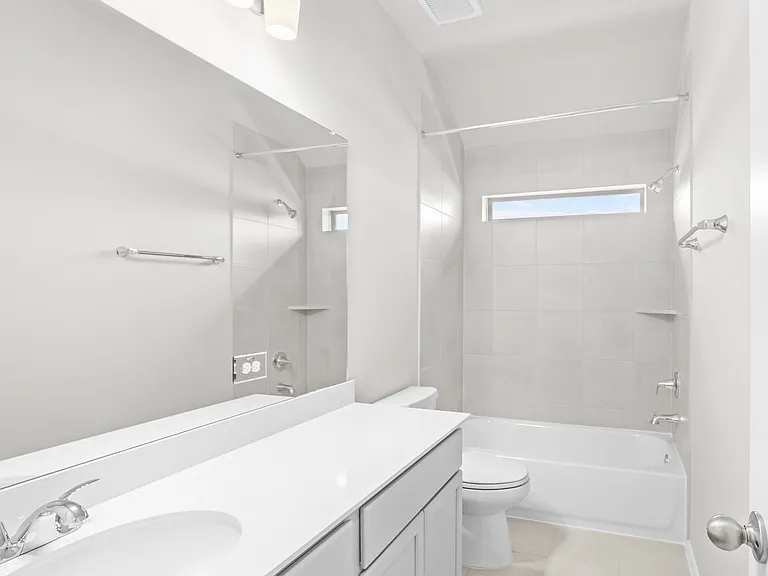 Full secondary bathroom with single vanity, quartz countertop, tile tub/shower combo, and privacy window.