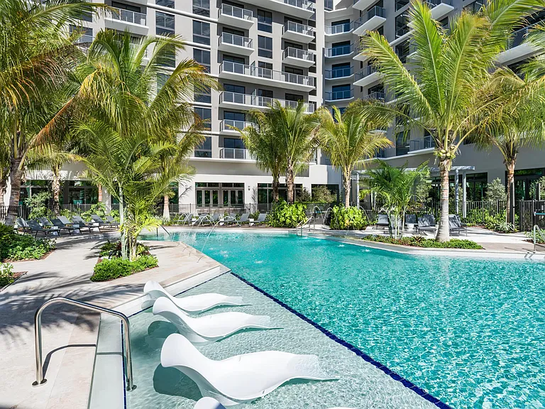 Palm-lined pool design pairs sculpted loungers and crisp tile edges, creating a resort-inspired setting framed by clean architecture and layered greenery.