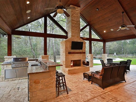 Stunning outdoor kitchen and living area! Vaulted wood ceiling, plus stone fireplace! Stamped concrete patio Plus HUGE bar area complete with refrigerator, grill, cooktop, large sink!