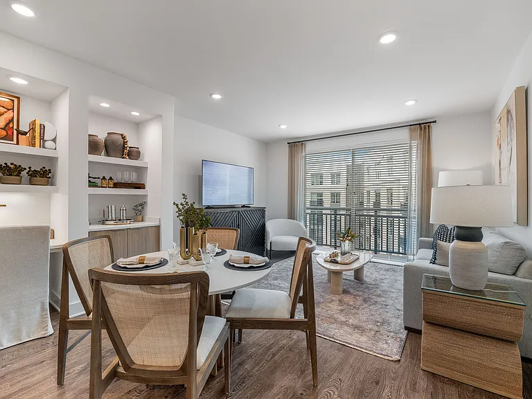 Elegant living area with natural light, featuring a cozy sofa, stylish dining table, and modern decor, perfect for a welcoming home atmosphere.