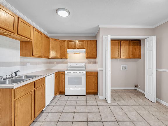 A kitchen space separated from the living room with a washer and dryer, stove, oven/range/stove, garbage disposal, dishwasher and fridge. A washer and dryer have been installed after this picture was taken..