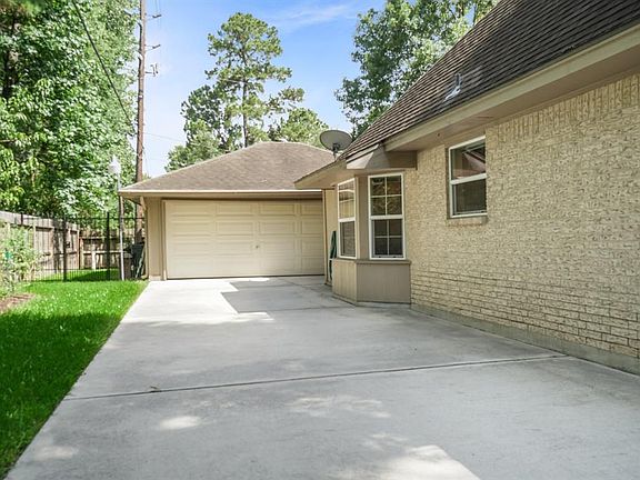 Two car detached garage is tucked back with fully fenced back yard. Wrought iron fence beside garage. View shows the updated and extended driveway and the breakfast room bay window.