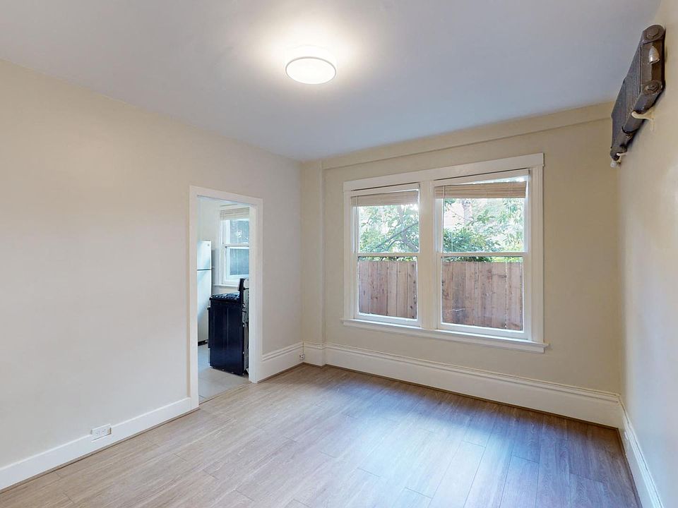 Sunlit room with a large window and wood-like flooring