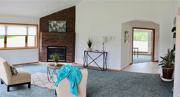 Large open great room with brick fireplace and dramatic vaulted ceilings.  French doors off tile entry lead into ample den/office.