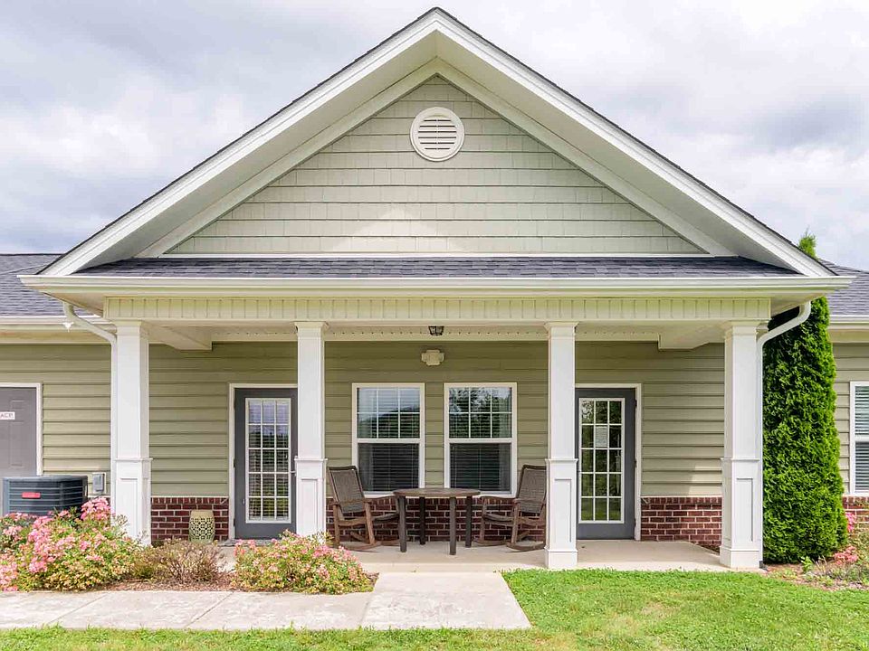 Inviting clubhouse exterior with covered front porch, patio seating, and manicured landscaping at Cedar Terrace Apartments.
