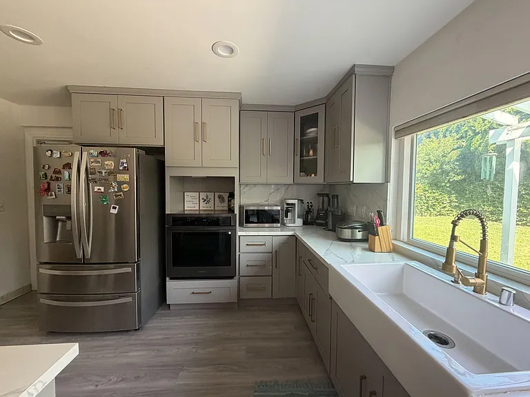 Updated kitchen with ample shaker cabinetry, stainless appliances, generous counters, and a large sink under a picture window