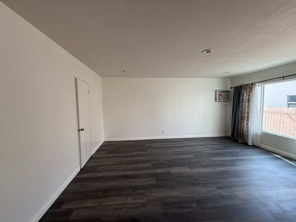 Large living room with new floors and paint and ample natural light with large windows.