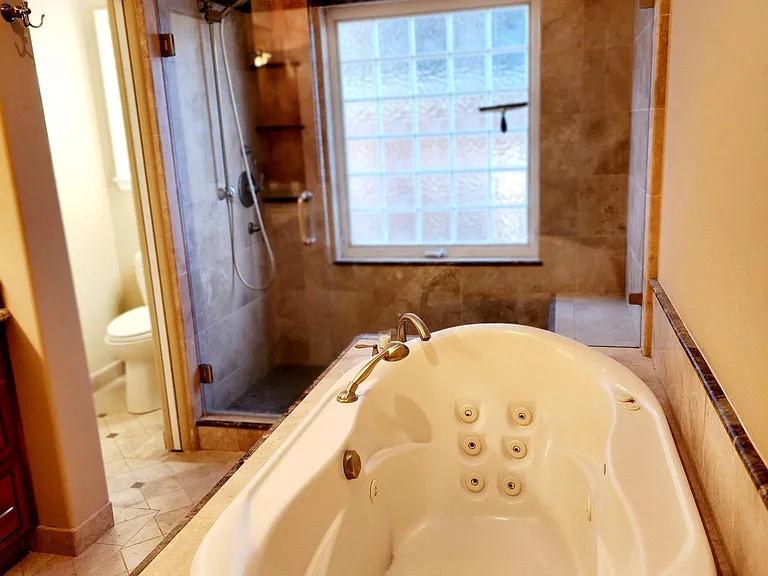 Primary bathroom with beautiful custom tile, cabinets, vanity, jacuzzi tub, large walk in shower and separate private toilet closet.
