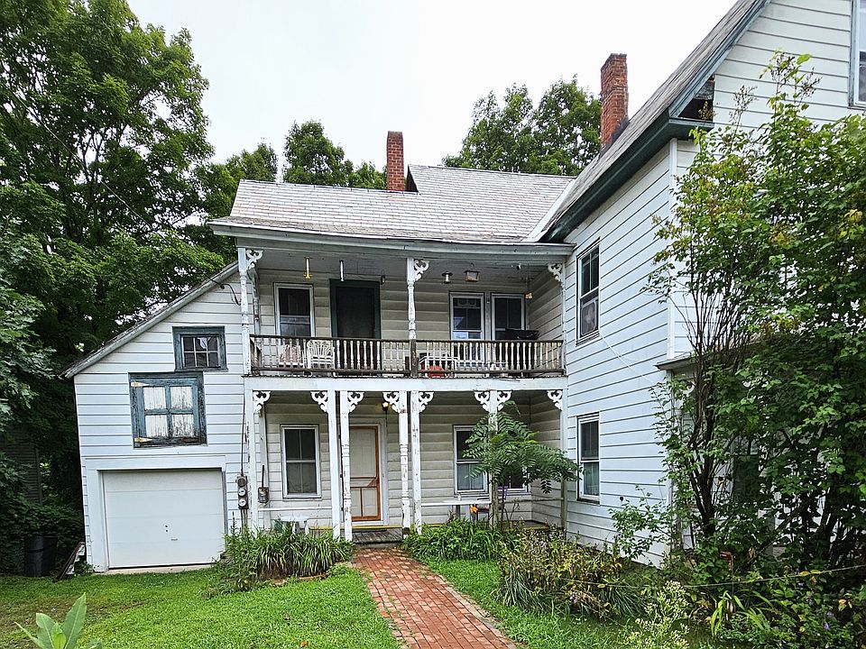 Brick side walk leads to outside entrance to apartment #1 with porch.