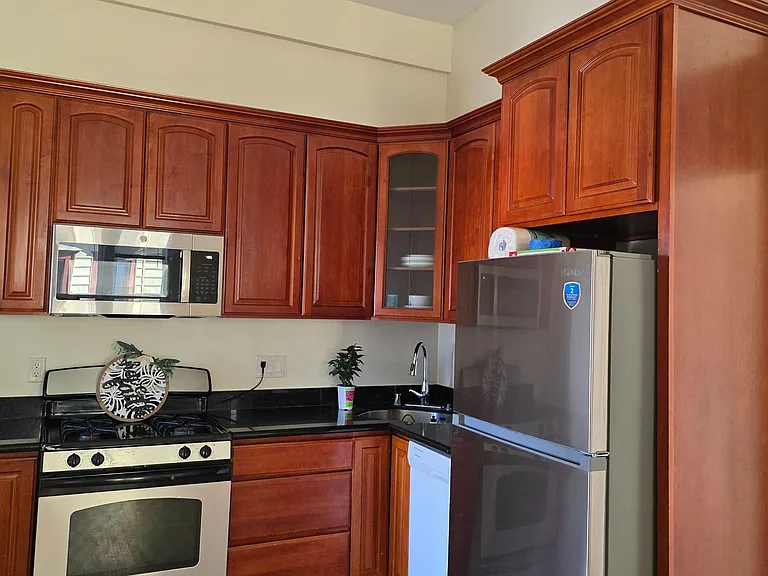 Functional kitchen with ample wood cabinetry, black countertops, and a full appliance package including gas range and microwa