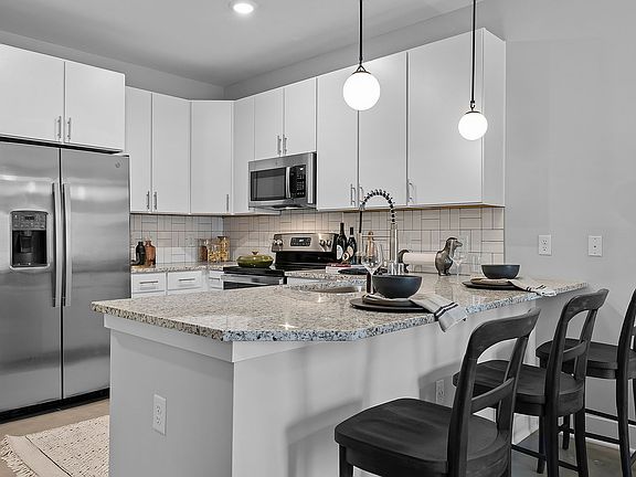 Kitchen with granite counters, stainless appliances, and subway tile backsplash