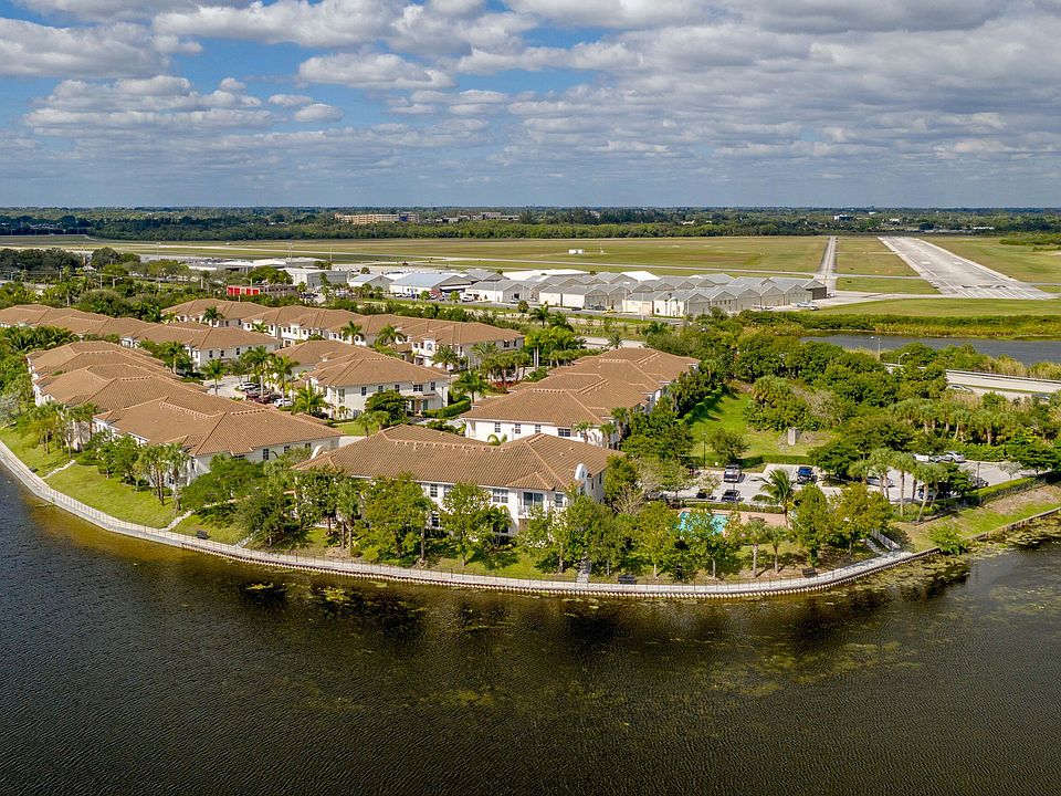 Aerial view of elegant lakeside apartments with charming terracotta roofs surrounded by lush greenery and scenic water views, enhancing a serene lifestyle.