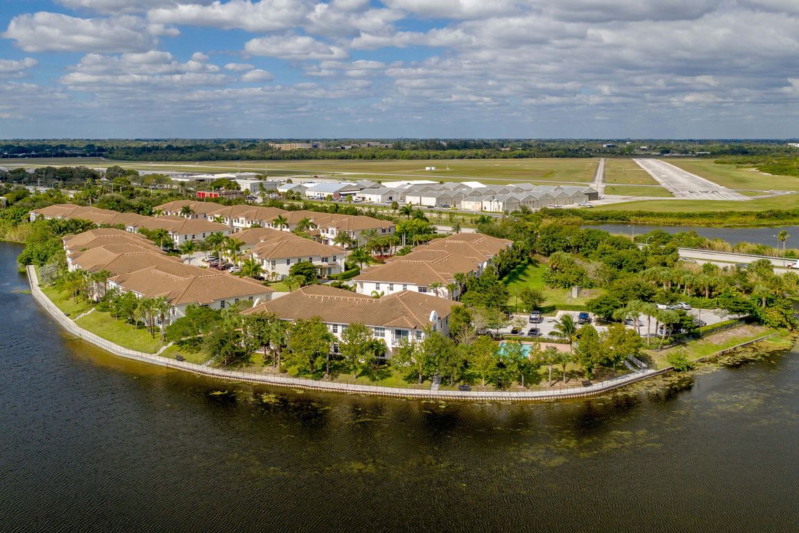 Aerial view of elegant lakeside apartments with charming terracotta roofs surrounded by lush greenery and scenic water views, enhancing a serene lifestyle.