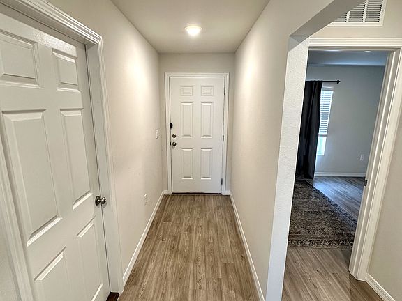 Looking back toward entryway with front bedroom on the right. Attached garage door on the left