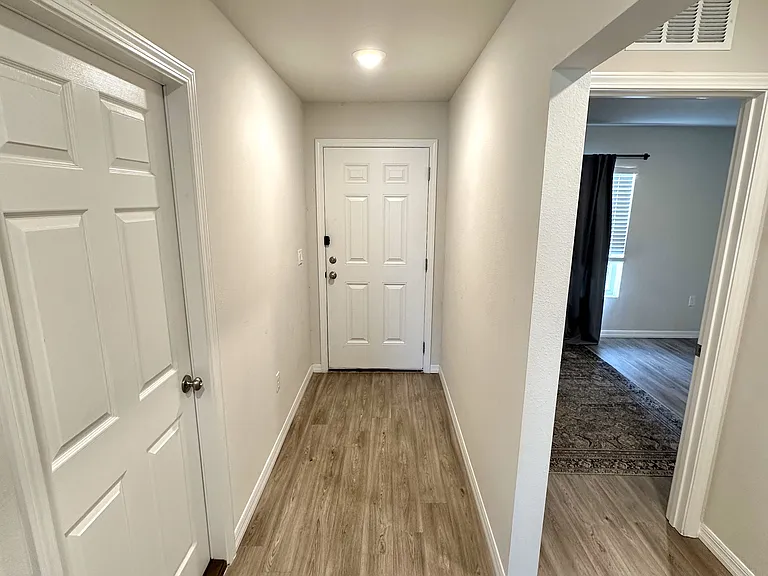 Looking back toward entryway with front bedroom on the right. Attached garage door on the left