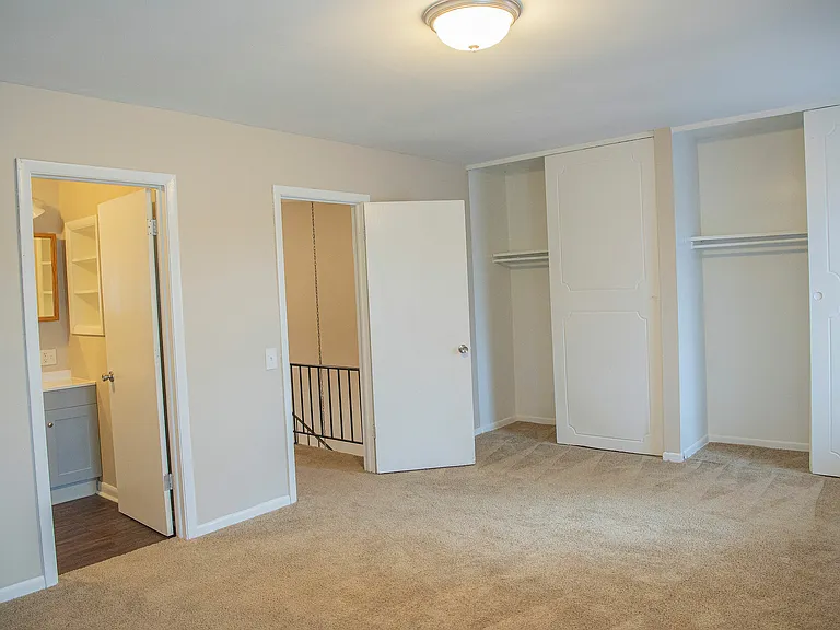 Bright, spacious bedroom with plush carpeting, ample closet space, and elegant neutral tones.