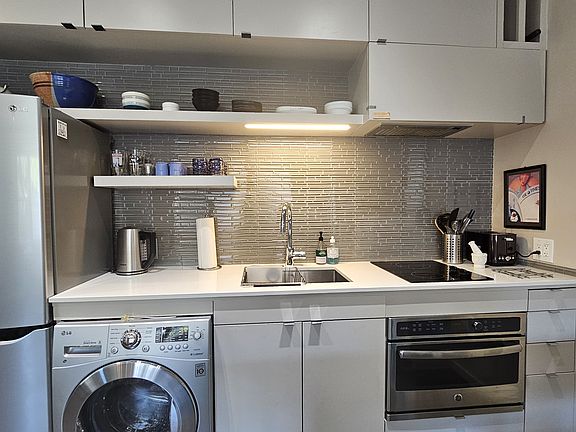 Modern kitchen appliances including frig/freezer, combo washer/dryer, sink disposal, 2-burner smooth-top range, and combo micro/convection oven.