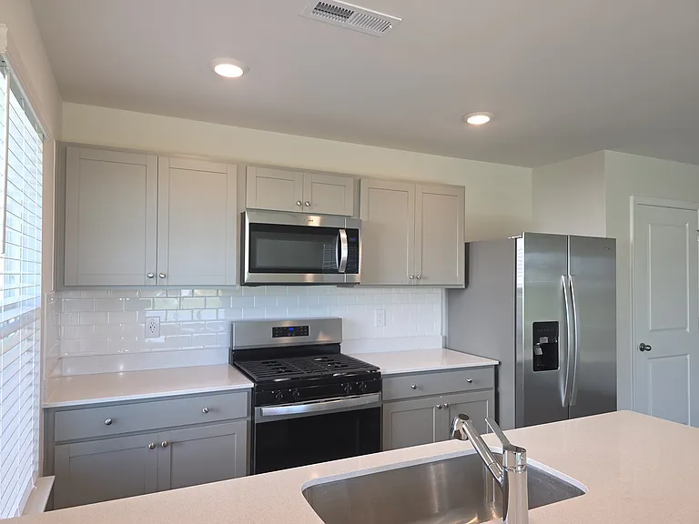 Kitchen features a sleek white backsplash
